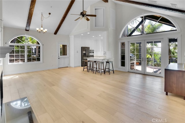 interior space featuring ceiling fan with notable chandelier, french doors, light wood-type flooring, high vaulted ceiling, and beam ceiling