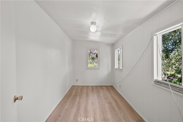 empty room with lofted ceiling, light wood-type flooring, and a healthy amount of sunlight