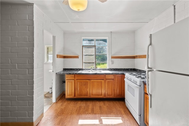 kitchen featuring light hardwood / wood-style floors, sink, brick wall, and white appliances