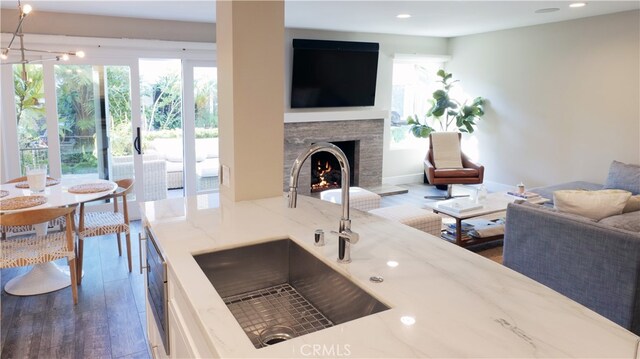 kitchen with light stone countertops, sink, and dark wood-type flooring