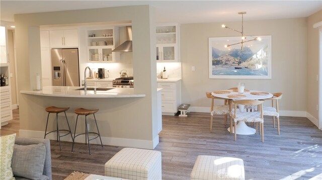 kitchen with appliances with stainless steel finishes, dark wood-type flooring, wall chimney range hood, sink, and white cabinetry