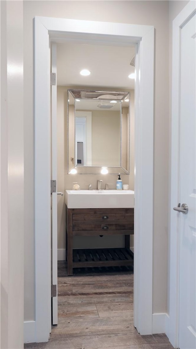 bathroom with wood finished floors, vanity, and baseboards