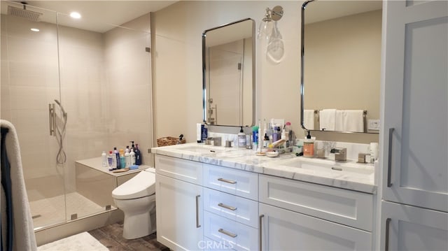 full bathroom featuring double vanity, a stall shower, a sink, and toilet