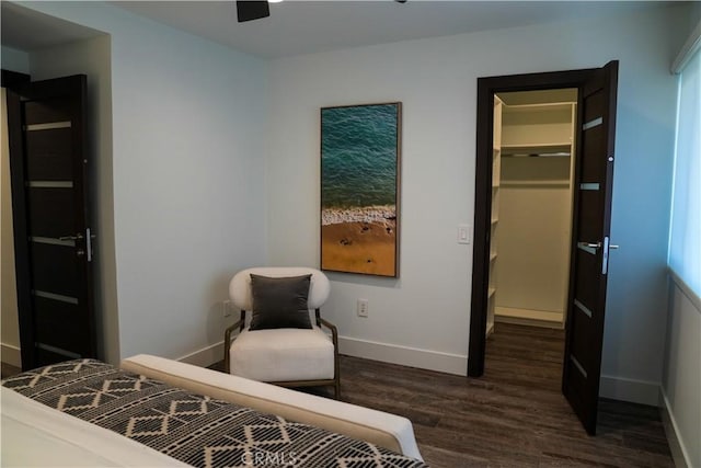 bedroom with a closet, baseboards, a walk in closet, and dark wood finished floors