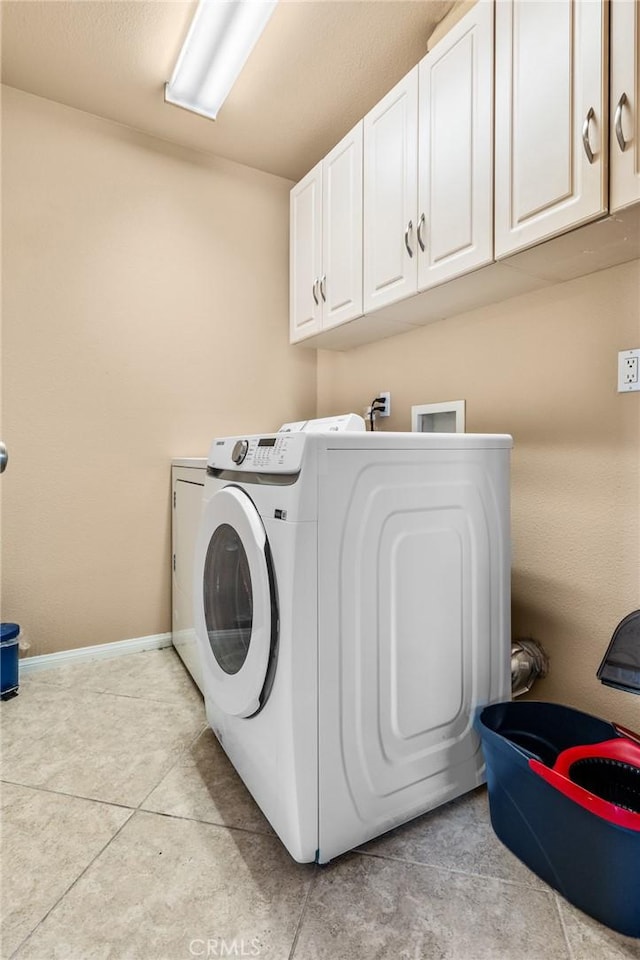 clothes washing area with washer and dryer, light tile patterned floors, and cabinets