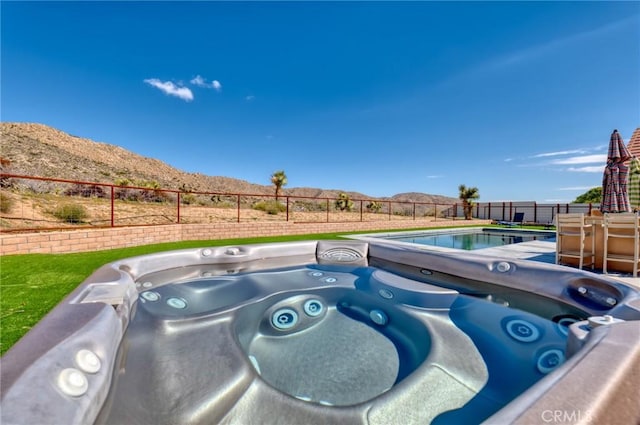 view of pool with a mountain view and a hot tub