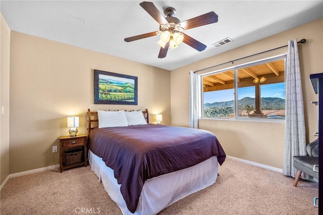 bedroom with a mountain view, light carpet, and ceiling fan