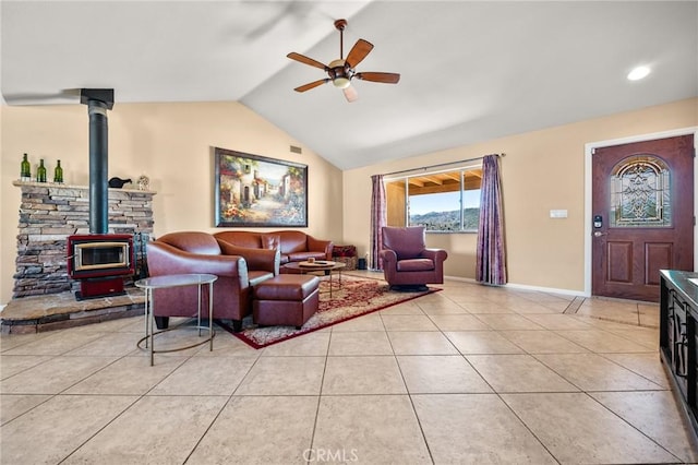 tiled living room featuring vaulted ceiling, a wood stove, and ceiling fan