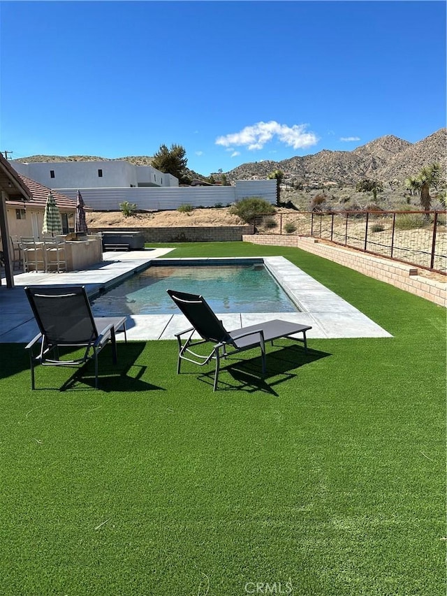 view of swimming pool with a mountain view and a lawn