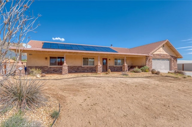 view of front facade with covered porch, a garage, and solar panels