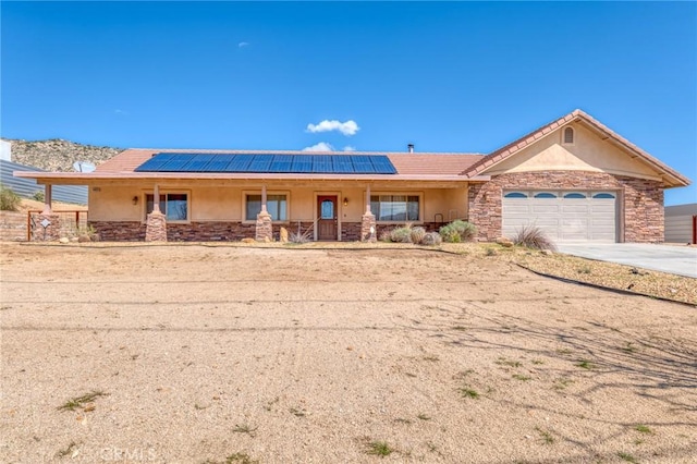 view of front of house featuring solar panels, a garage, and covered porch