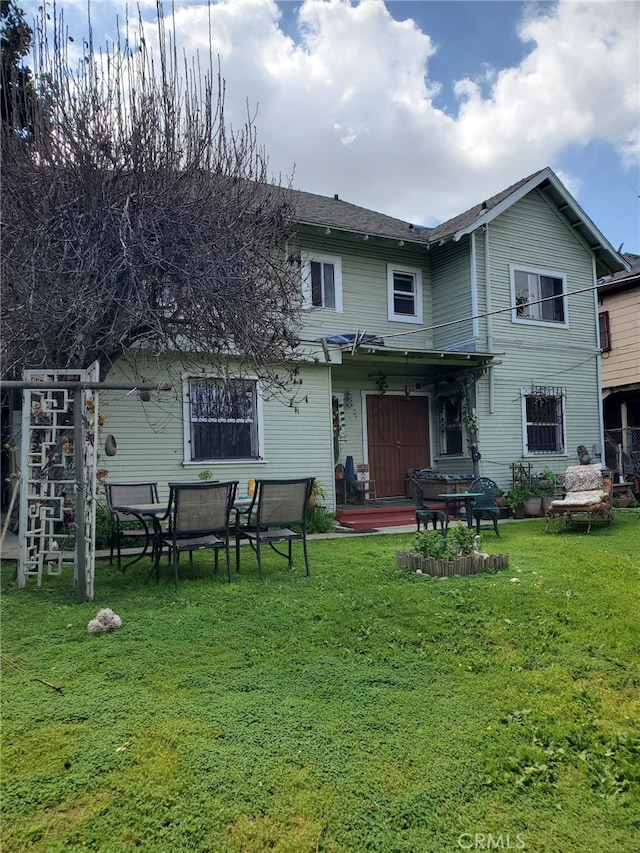 rear view of property featuring a lawn and a patio area