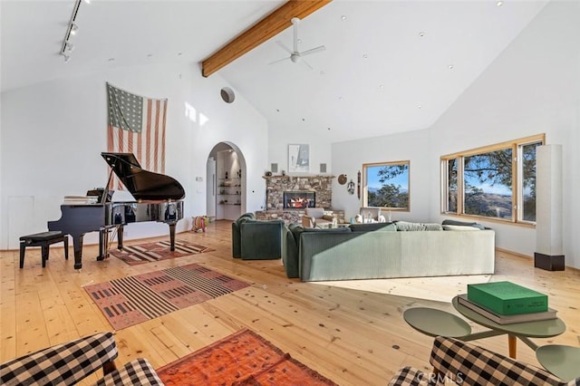 living room featuring light hardwood / wood-style floors, a stone fireplace, high vaulted ceiling, and ceiling fan