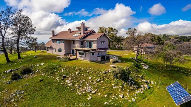 rear view of house with a lawn and a balcony