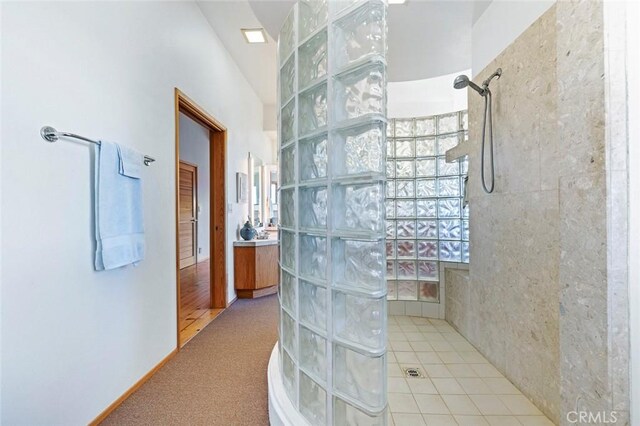 bathroom with vanity, a tile shower, and tile patterned floors