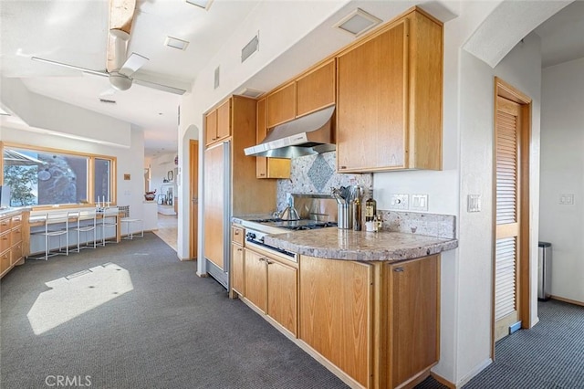 kitchen with stainless steel gas cooktop, ceiling fan, tasteful backsplash, and dark carpet