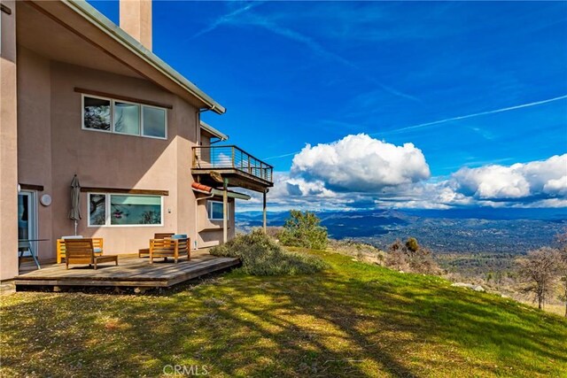 view of yard with a balcony and a wooden deck