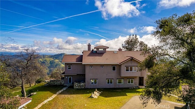 back of property with a mountain view and a lawn