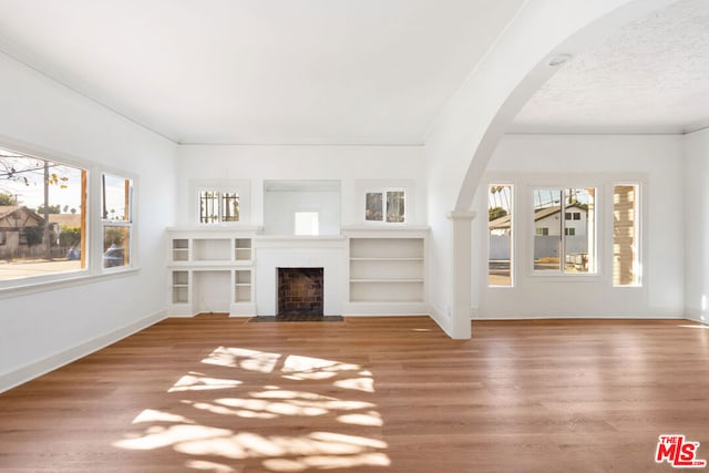 unfurnished living room featuring wood-type flooring, plenty of natural light, and a textured ceiling