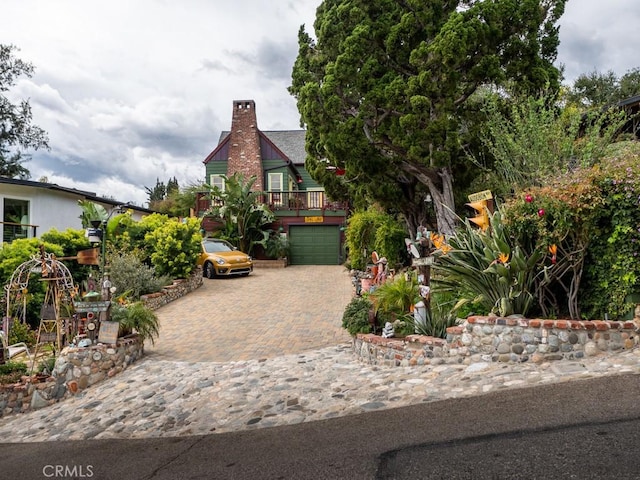 view of front facade featuring a garage, a chimney, and decorative driveway