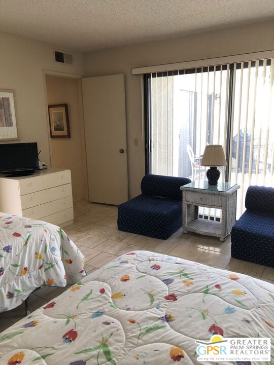 tiled bedroom with multiple windows and a textured ceiling