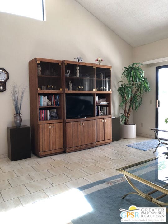 living room with light tile patterned flooring and high vaulted ceiling