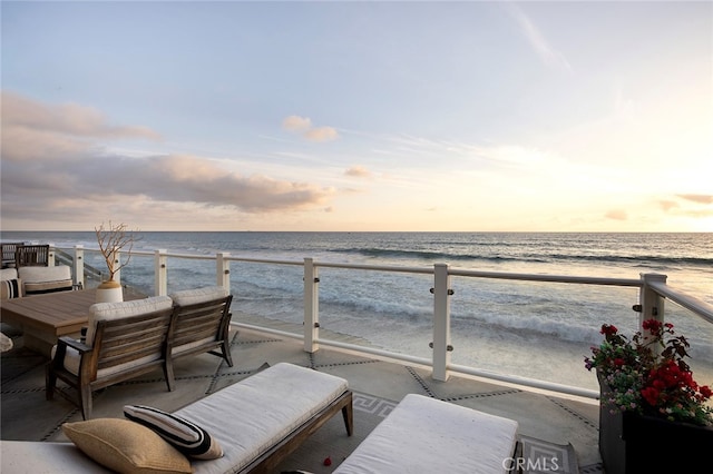 balcony at dusk with a view of the beach and a water view