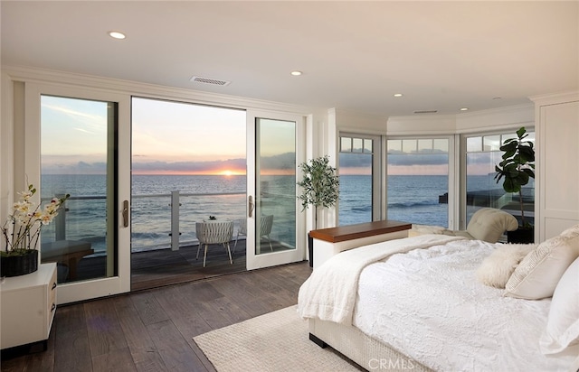 bedroom with a water view, multiple windows, and dark hardwood / wood-style flooring