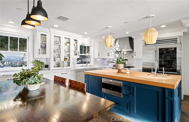 kitchen featuring blue cabinets, pendant lighting, wooden counters, and white cabinets