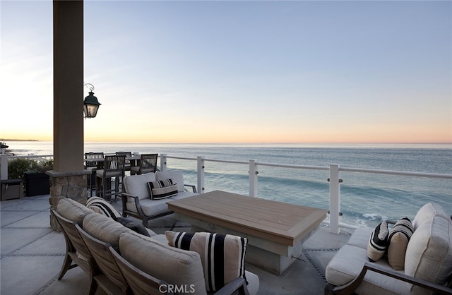 patio terrace at dusk featuring outdoor lounge area and a water view