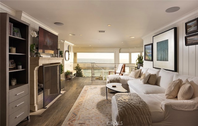 living room with ornamental molding, a tiled fireplace, and dark wood-type flooring