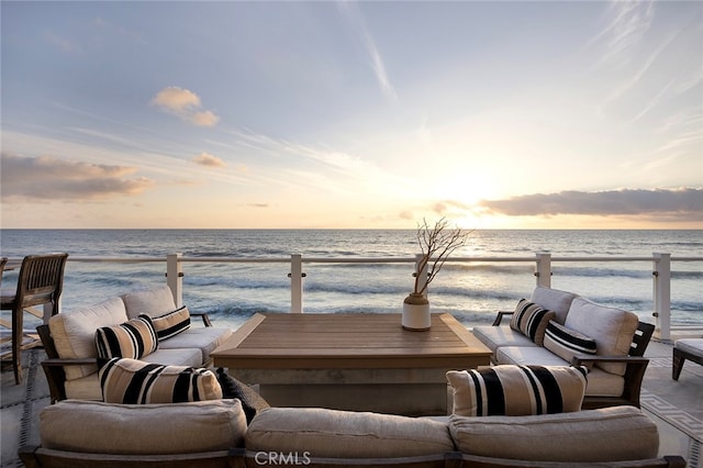 patio terrace at dusk featuring a view of the beach and a water view