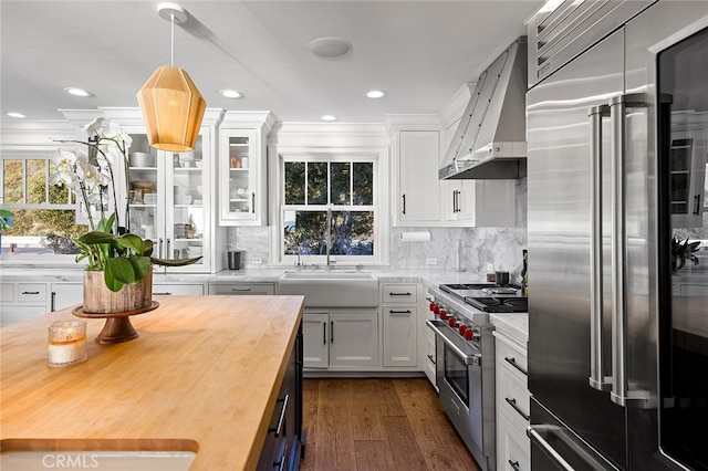 kitchen with white cabinets, high end appliances, wooden counters, dark hardwood / wood-style floors, and wall chimney range hood