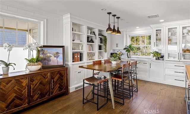 kitchen featuring white cabinetry, dark wood-type flooring, a breakfast bar, decorative light fixtures, and ornamental molding