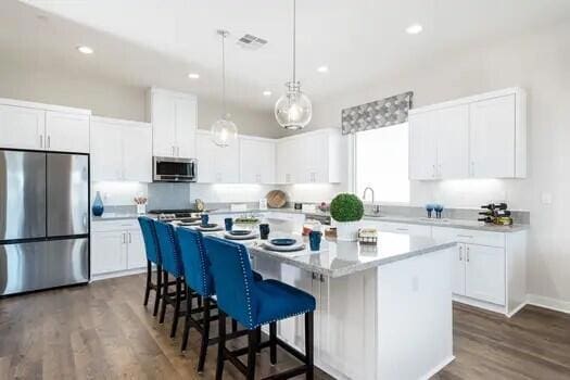 kitchen with appliances with stainless steel finishes, white cabinets, a center island, and dark hardwood / wood-style floors