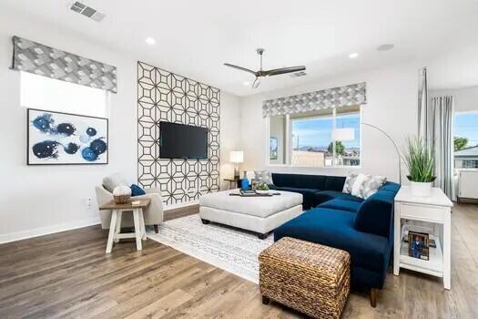 living room with a wealth of natural light, wood-type flooring, and ceiling fan