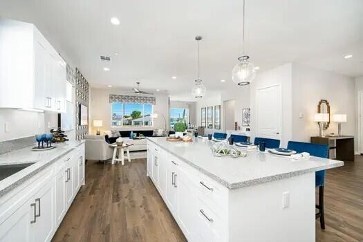 kitchen featuring dark hardwood / wood-style floors, a kitchen breakfast bar, hanging light fixtures, a center island, and white cabinets