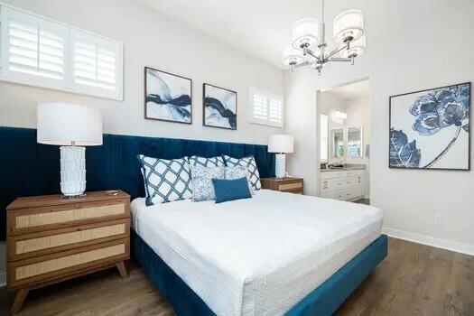 bedroom with ensuite bath, a notable chandelier, and dark hardwood / wood-style floors