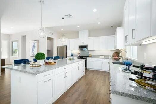 kitchen featuring white cabinetry, stainless steel appliances, sink, and a kitchen island