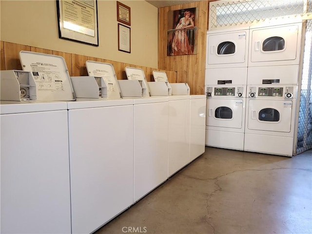 washroom featuring stacked washer and clothes dryer, wood walls, and washing machine and clothes dryer