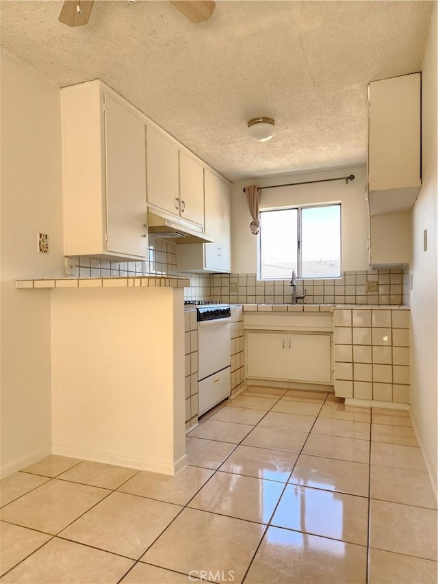 kitchen with ceiling fan, tasteful backsplash, white range oven, a textured ceiling, and light tile patterned flooring