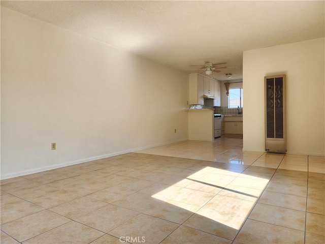 tiled empty room featuring ceiling fan and sink