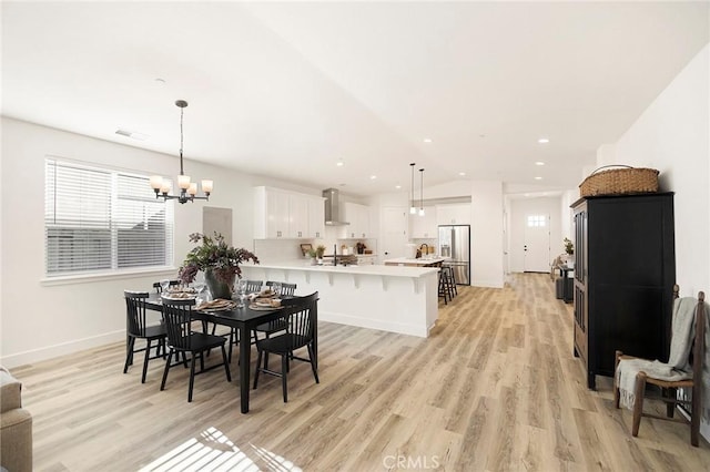 dining space featuring a chandelier, sink, and light hardwood / wood-style flooring