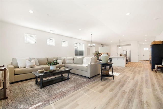 living room featuring light wood-type flooring, an inviting chandelier, and a healthy amount of sunlight