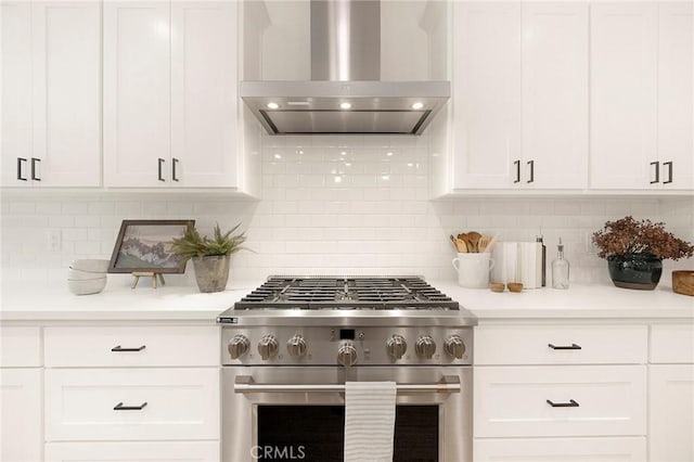 kitchen featuring decorative backsplash, white cabinetry, high end stainless steel range, and wall chimney exhaust hood