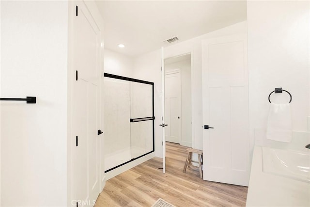 bathroom with hardwood / wood-style floors, an enclosed shower, and sink