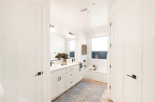 bathroom with a bath, vanity, and hardwood / wood-style flooring