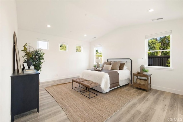 bedroom featuring light hardwood / wood-style flooring, multiple windows, and lofted ceiling