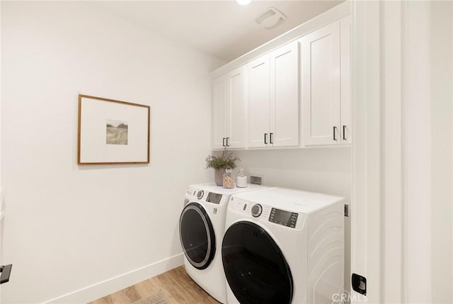 clothes washing area featuring cabinets, light wood-type flooring, and washing machine and clothes dryer