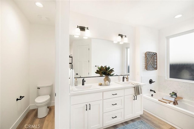 bathroom featuring a tub, vanity, wood-type flooring, and toilet